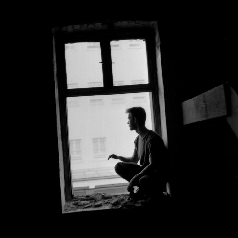 A man squatting on a windowsill