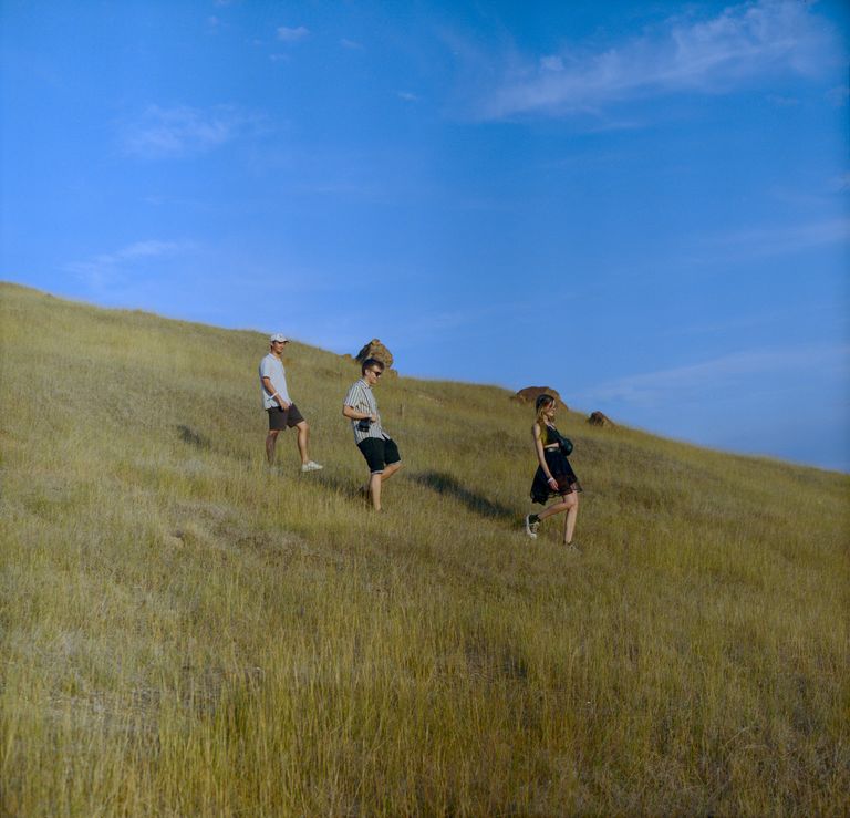 Two boys and a girl walking on a polluted meadow