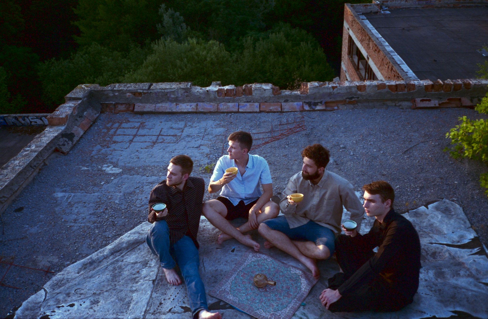 Four boys enjoying a tea together on a rooftop sunset