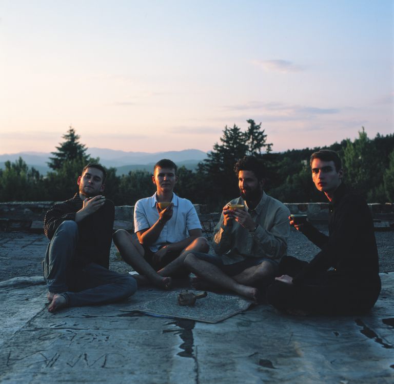 Four boys enjoying a tea together on a rooftop during sunset