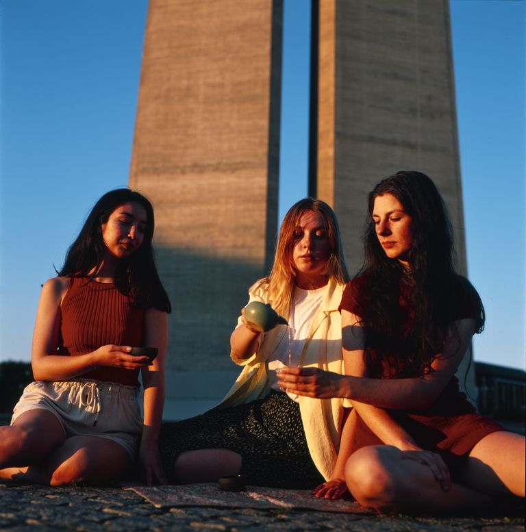 Three girls drinking tea in front of metro ventilation
