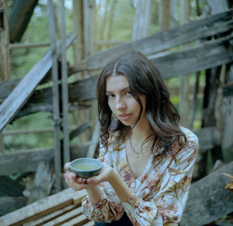 A detail of a girl with a tea cup on a derelict balcony