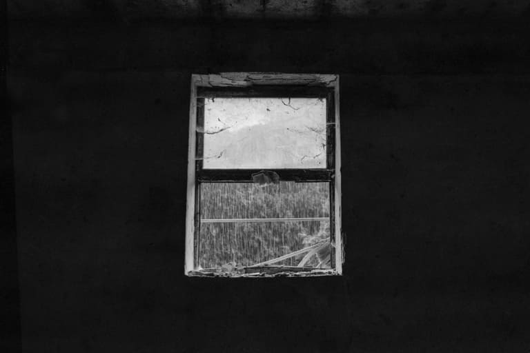 A window in a ruined collective farm with rain
